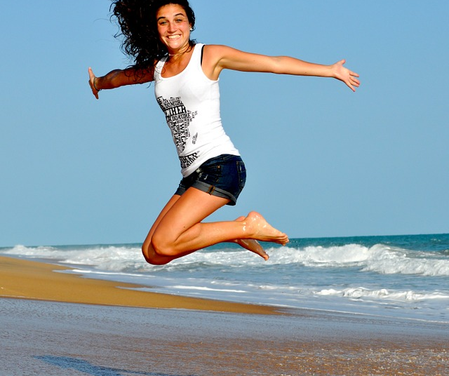 A woman is jumping in the air on the beach
